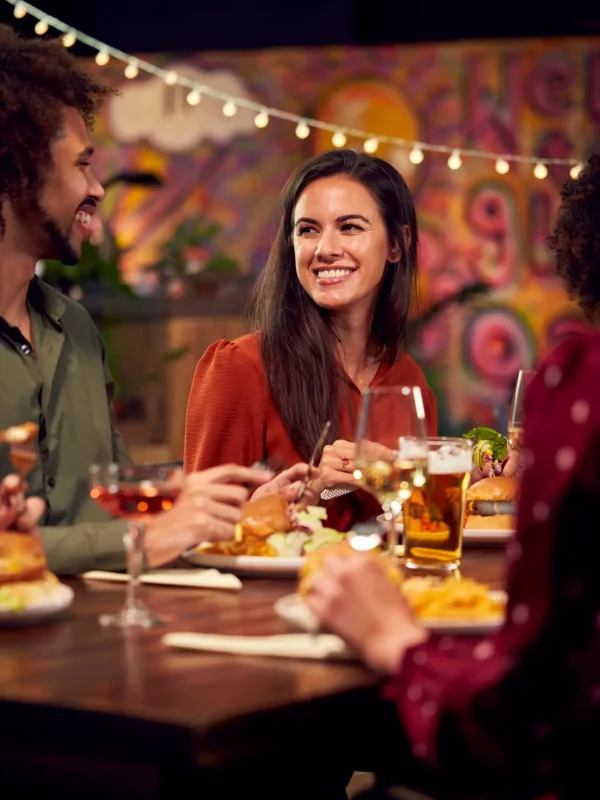 Group Of Friends Enjoying Night Out Eating Meal In Restaurant Together